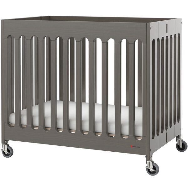 A Foundations Boutique grey slatted wood folding crib with wheels.