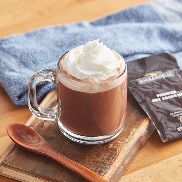 A glass mug of Ghirardelli hot chocolate with a spoon.