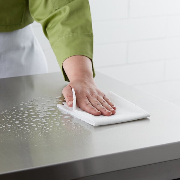 A person cleaning a surface with a white ChoiceHD foodservice wiper.