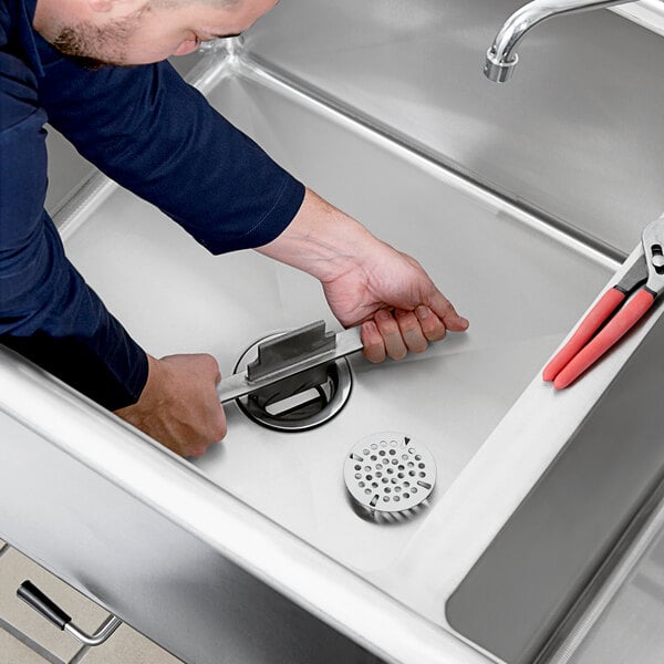 A man using a Lever / Twist Waste Valve tool to fix a sink drain.