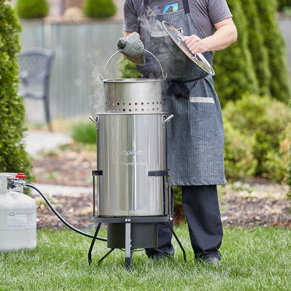 A man wearing an apron cooking outside with a Backyard Pro Seafood Boiler and Steamer Kit.