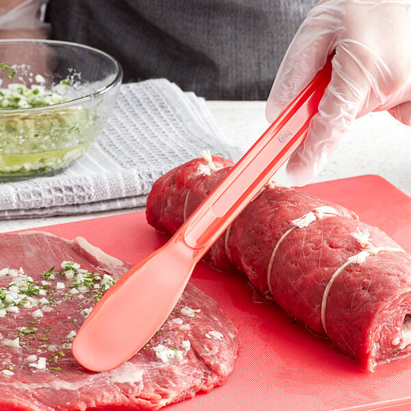 A person using a Choice sandwich spreader to cut meat on a cutting board.
