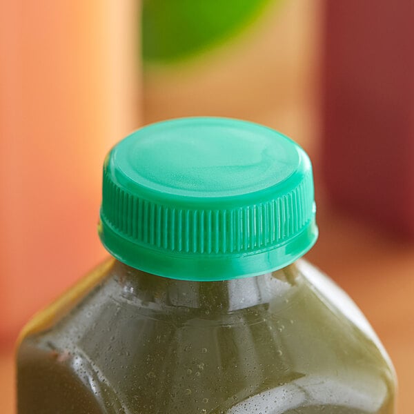 A green juice bottle with a green tamper-evident cap sitting on a counter.