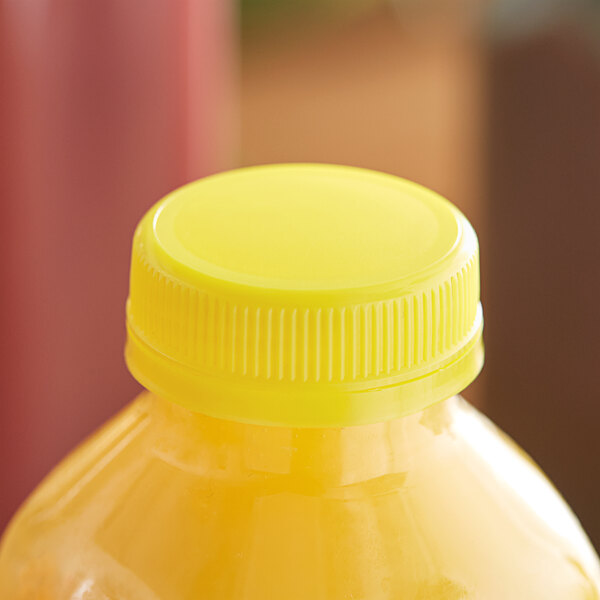 A close-up of a yellow plastic bottle cap on a yellow juice bottle.