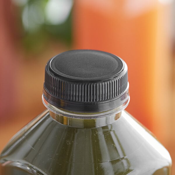 A bottle of green juice with a black tamper-evident cap on a counter.