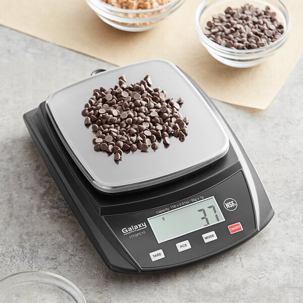 A Galaxy PC10 digital portion scale with a pile of chocolate chips on it.