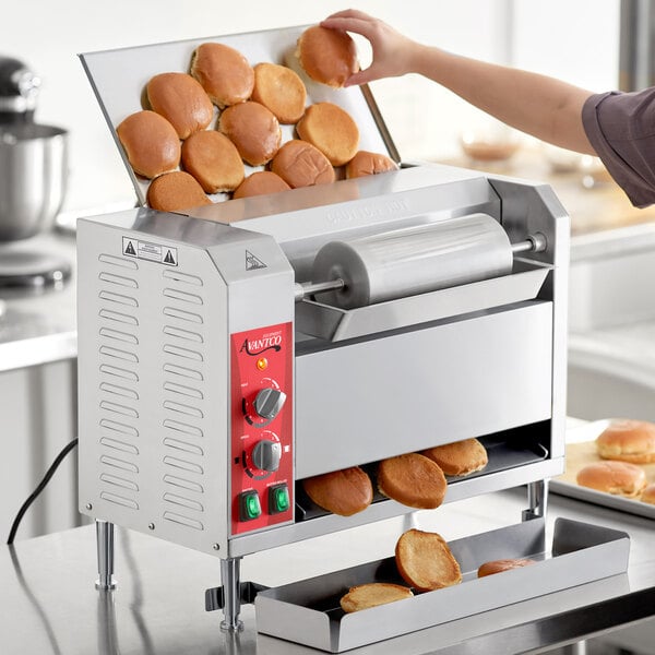 A person using an Avantco vertical conveyor bun toaster to toast buns in a professional kitchen.