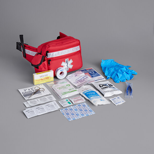 A red Medique fanny pack first aid kit with various items on the side.