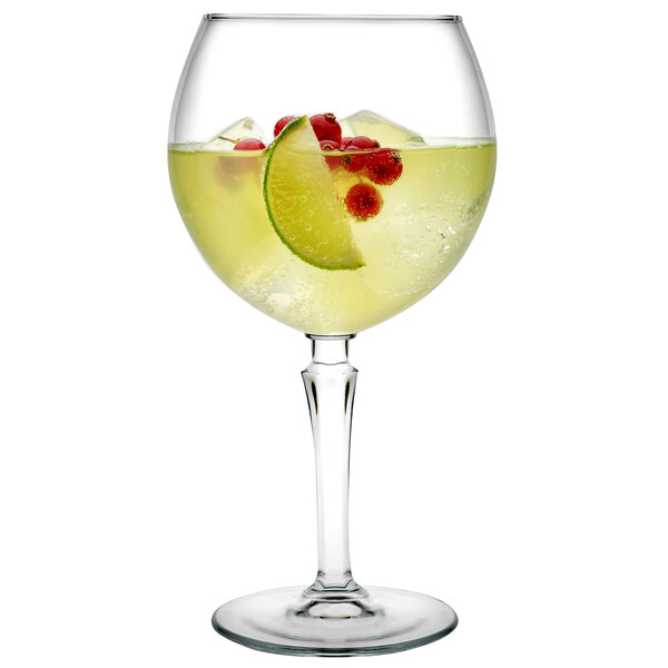 A Pasabahce Hudson gin and tonic glass with a yellow drink and fruit garnish.