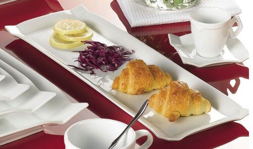 A CAC rectangular white china platter with croissants and salad on it.