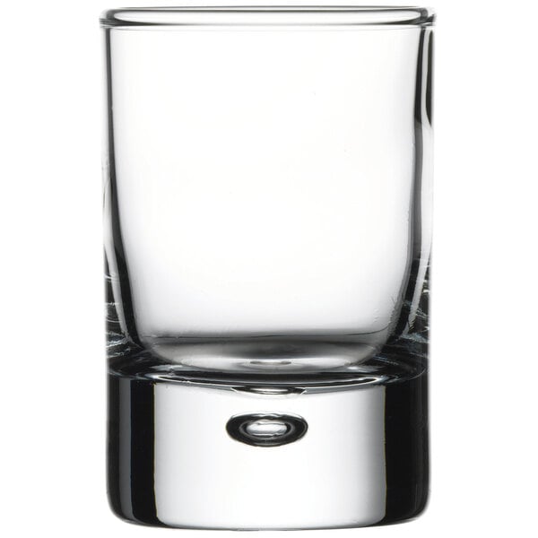 A close up of a Pasabahce clear shot glass with a small bubble.