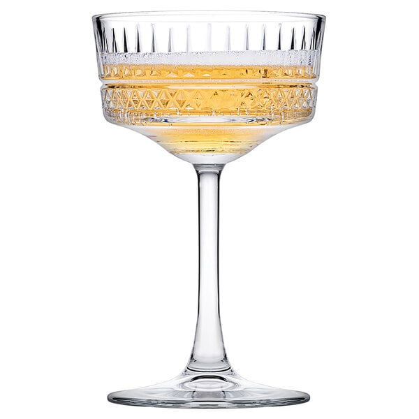 A Pasabahce Elysia coupe glass with yellow liquid in it.