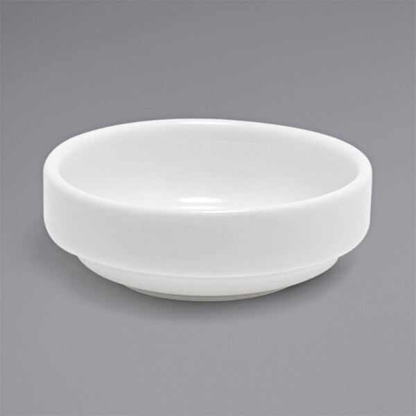 A Front of the House bright white porcelain ramekin on a gray surface.