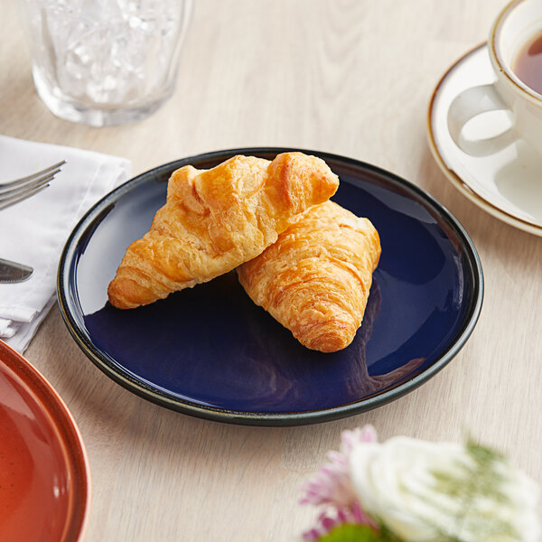 An Acopa Keystone Azora Blue stoneware coupe plate with croissants on it.