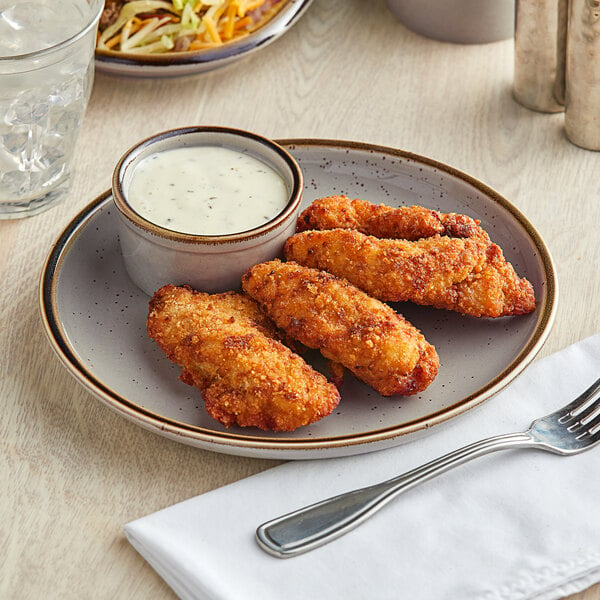 An Acopa Keystone granite gray stoneware coupe plate with fried chicken strips and sauce on a table next to a fork.