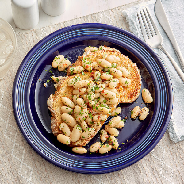 A white Acopa Capri stoneware plate with a plate of food topped with beans.