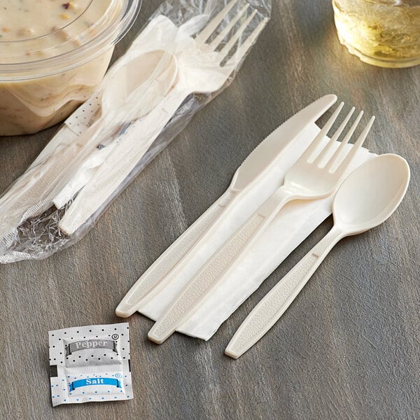 Wrapped Visions beige plastic cutlery next to a container of food.