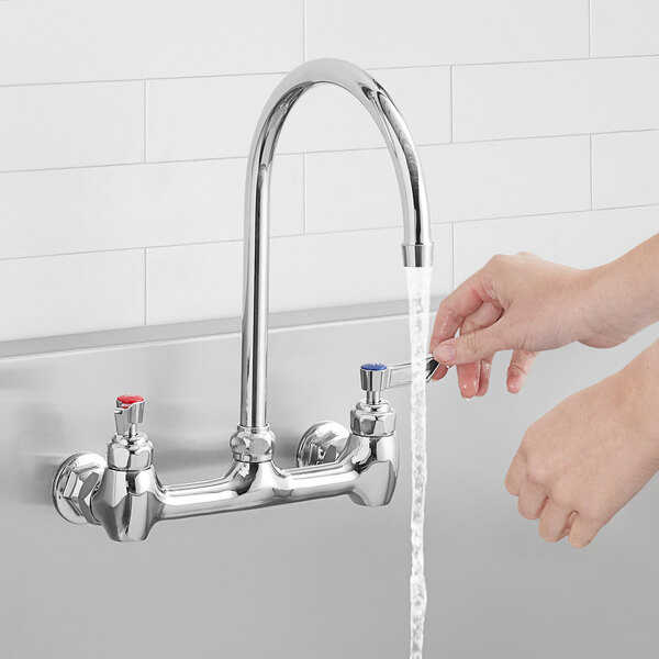 A person using a Waterloo 8" long gooseneck spout to pour water into a sink.