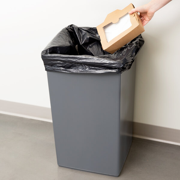 A hand putting a brown box into a Continental gray square trash can.