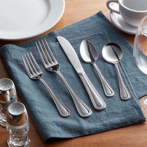Acopa Lydia stainless steel flatware on a blue napkin.