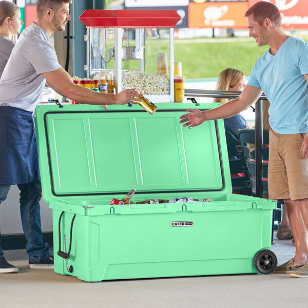 Two men standing next to a CaterGator Seafoam green cooler.