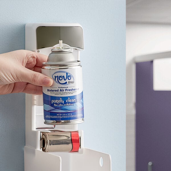 A hand holding a Noble Chemical Novo Purely Clean metered air freshener refill can.