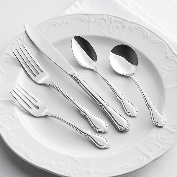 A plate with Acopa stainless steel flatware including a spoon, fork, and knife.