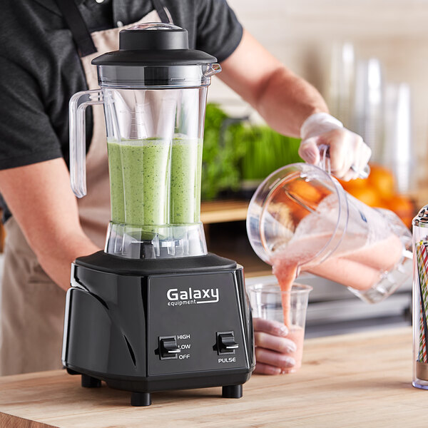 A person pours a green smoothie into a Galaxy commercial blender.
