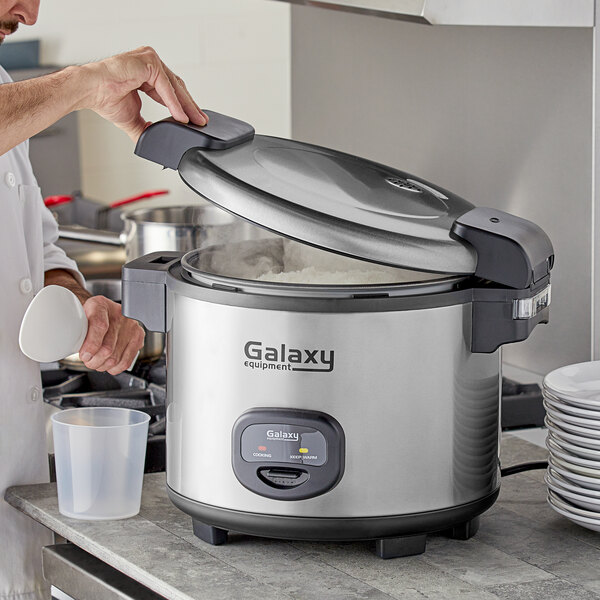 A person using a Galaxy commercial rice cooker to prepare food.
