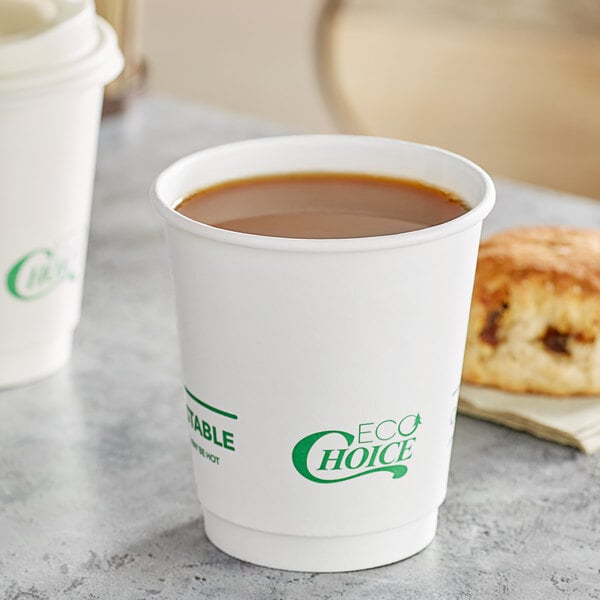 A white EcoChoice double wall paper hot cup on a counter with a cup of coffee and a pastry.