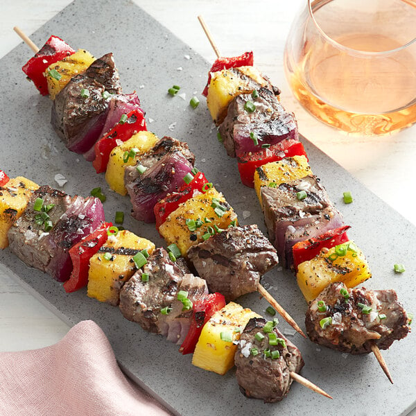 EcoChoice wooden skewers with grilled beef and pineapple on a plate.