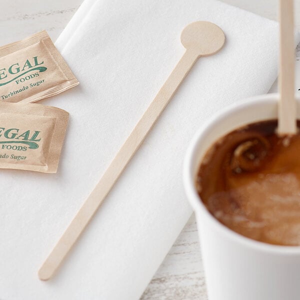 A cup of coffee with a Choice wooden coffee stirrer on a table.