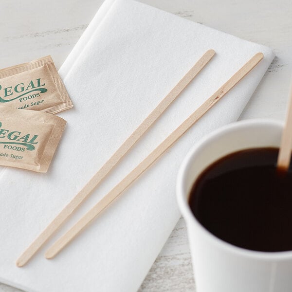 A cup of coffee with a Choice wooden stirrer on a table.