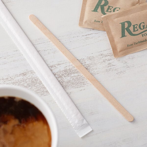 A cup of coffee with a Choice wooden coffee stirrer on a table.