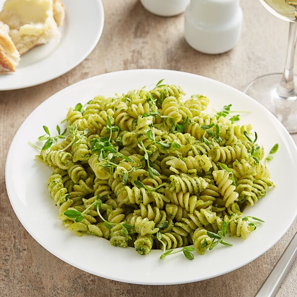 A plate of Barilla rotini pasta with pesto sauce and herbs on a table in an Italian restaurant.