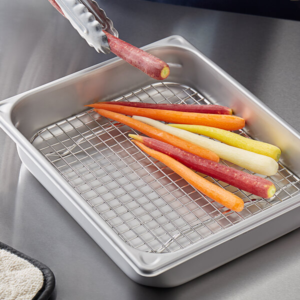 A Vigor stainless steel wire pan grate holding a tray of carrots on a counter.