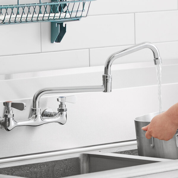 A person using a 15" double-jointed swing spout to wash dishes in a sink.