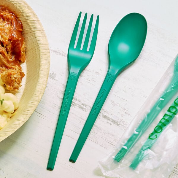A bowl of food with a green EcoChoice CPLA spoon and fork on the table.