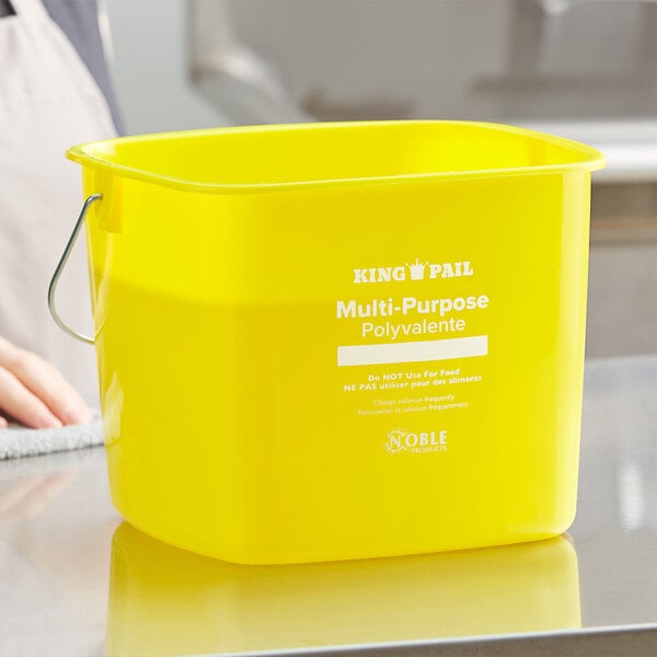 A woman standing in front of a yellow Noble Products King-Pail on a counter.