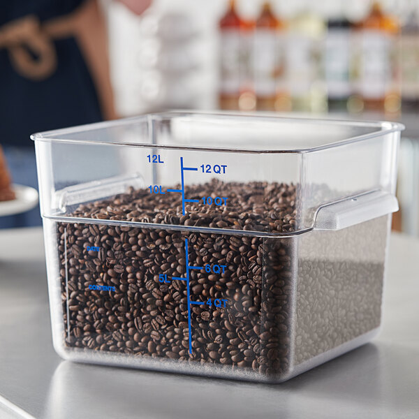 A Carlisle clear square polycarbonate food storage container filled with coffee beans on a counter.