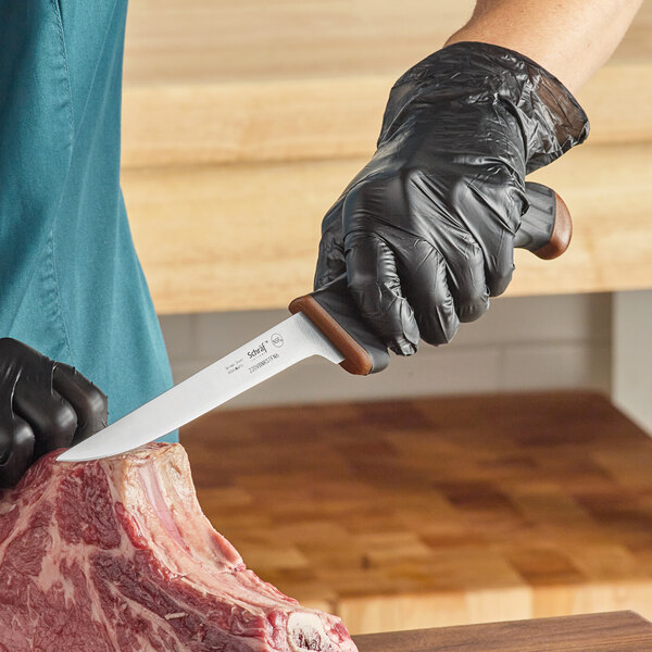 A person in black gloves using a Schraf narrow stiff boning knife to cut meat.