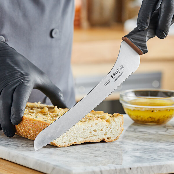 A person in black gloves using a Schraf serrated bread knife to cut bread.