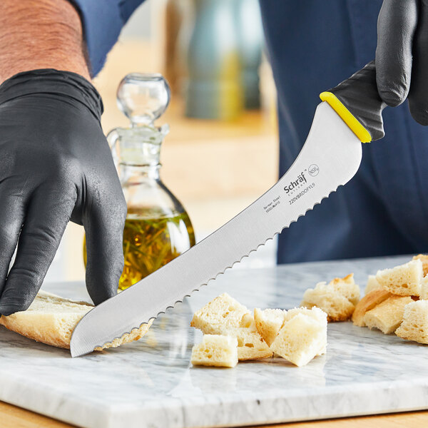 A person in black gloves using a Schraf serrated bread knife to cut bread.