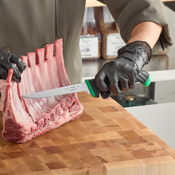 A person in black gloves using a Schraf narrow boning knife to cut meat on a wooden surface.