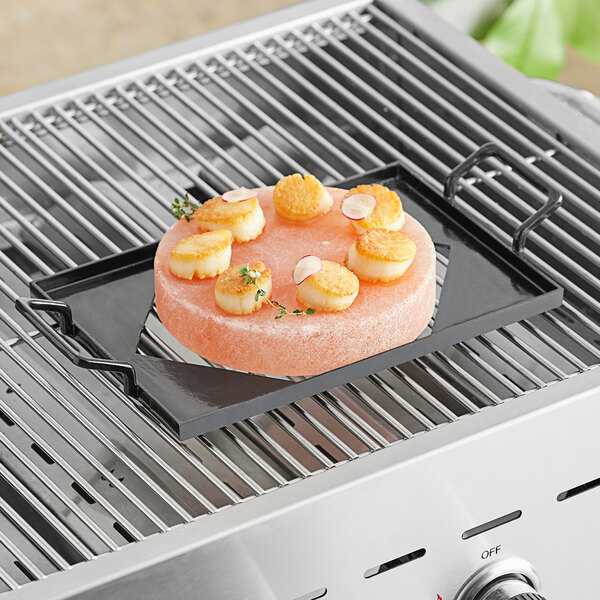 A pink Himalayan salt slab with scallops on a grill.