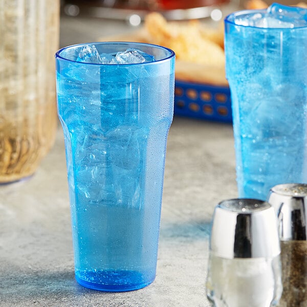 Two blue Choice plastic tumblers filled with ice water on a table.