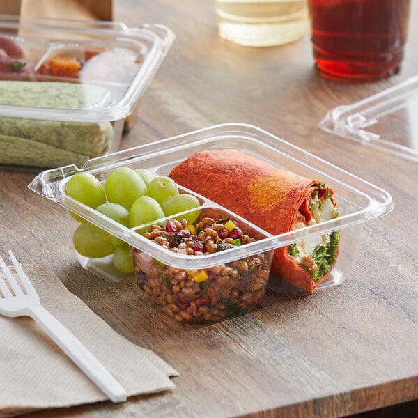 A plastic Dart deli container with food inside on a table.