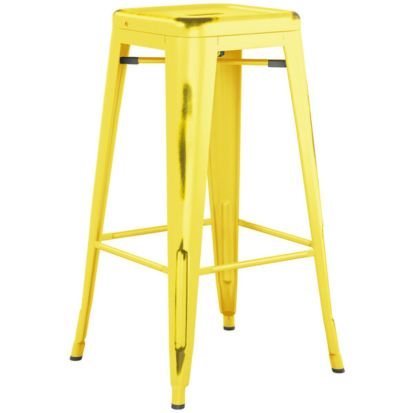 Lancaster Table & Seating Alloy Series Distressed Yellow Stackable Metal Indoor / Outdoor Industrial Barstool with Drain Hole Seat