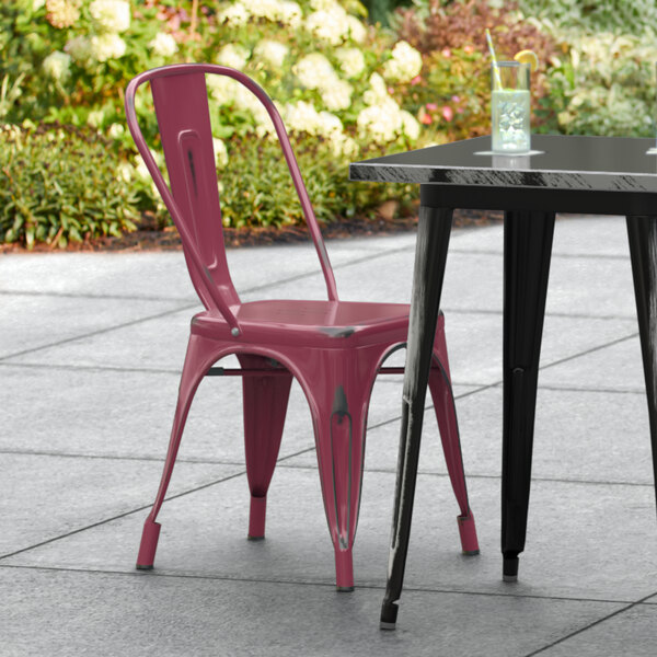 A Lancaster Table & Seating distressed mulberry metal chair on an outdoor patio.