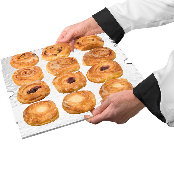 A person holding a tray of pastries with a Cal-Mil acrylic shelf.